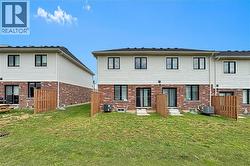 Rear exterior with a sloped grassy area, featuring brick and light-colored siding - 