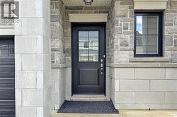 Contemporary stone facade featuring a black paneled entry door with glass inserts, black-framed window with grid, and light-colored block accents - 