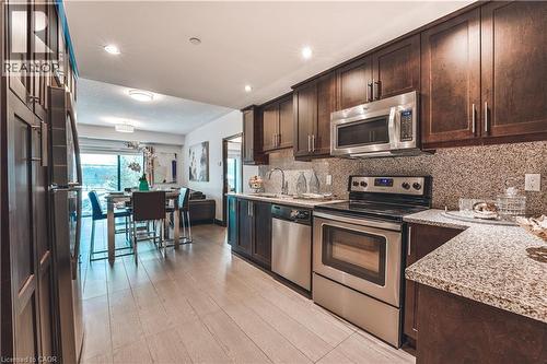 Kitchen featuring dark wood cabinetry, stainless steel appliances, speckled granite countertops, and a complementary backsplash - 1235 Richmond Street Unit# 1406, London, ON 