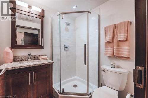 Bathroom featuring a dark wood vanity with a granite-style countertop, an undermount sink, and a framed mirror with integrated lighting - 1235 Richmond Street Unit# 1406, London, ON 