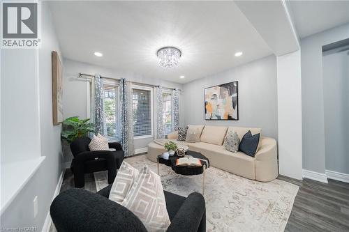 Living area featuring recessed lighting, a crystal chandelier, multiple windows with blinds, and wood-finish flooring - 151 Baldwin Drive, Cambridge, ON 