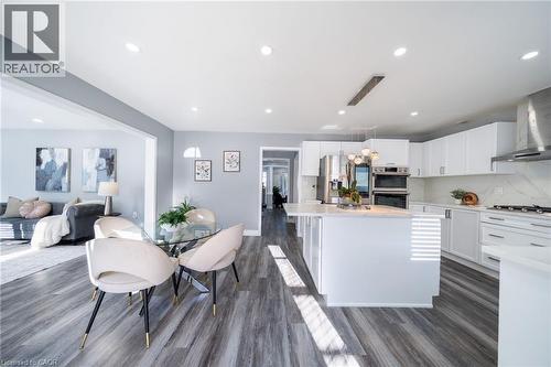 Modern kitchen featuring white cabinetry, stainless steel appliances, a center island with pendant lighting, and wood-finish flooring - 151 Baldwin Drive, Cambridge, ON 