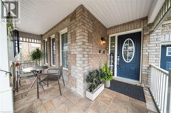 Covered porch entry featuring a dark blue door with oval glass insert, brick exterior, and stone tile flooring - 