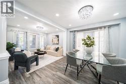 Open-concept living and dining areas featuring wood-finish flooring, recessed lighting, and a crystal chandelier - 