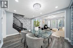 Open-concept dining area featuring a glass-top table, wood-finish flooring, and a crystal chandelier - 