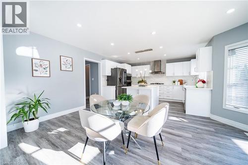 Open-concept kitchen and dining area featuring wood-finish flooring, recessed lighting, white cabinetry, a kitchen island, and stainless steel appliances - 151 Baldwin Drive, Cambridge, ON - Indoor Photo Showing Dining Room