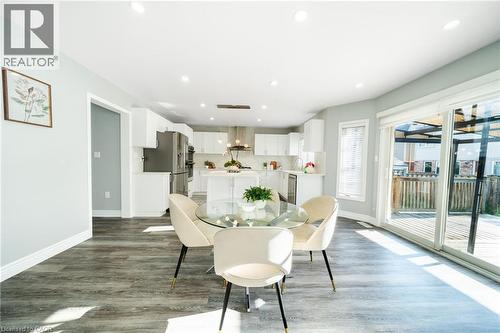 Open-concept living space featuring wood-finish flooring, recessed lighting, a modern kitchen with white cabinetry and stainless steel appliances, and a glass sliding door leading to an outdoor deck - 151 Baldwin Drive, Cambridge, ON - Indoor Photo Showing Dining Room
