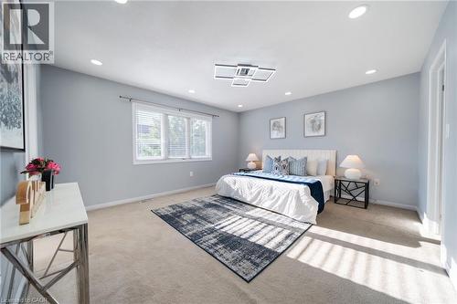 Carpeted bedroom with a three-panel window, recessed lighting, and a modern ceiling light fixture - 151 Baldwin Drive, Cambridge, ON - Indoor Photo Showing Bedroom