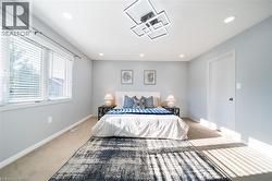 Spacious room featuring light-colored carpet flooring, recessed lighting, and a modern geometric ceiling fixture - 