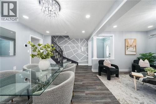 Open-concept main level featuring wood-finish flooring, recessed lighting, and a contemporary crystal chandelier - 151 Baldwin Drive, Cambridge, ON 