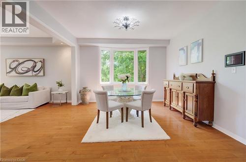 Open-concept dining area featuring wood-finish flooring, a contemporary chandelier, and a bay window - 23 Buerkle Court, Kitchener, ON - Indoor Photo Showing Dining Room