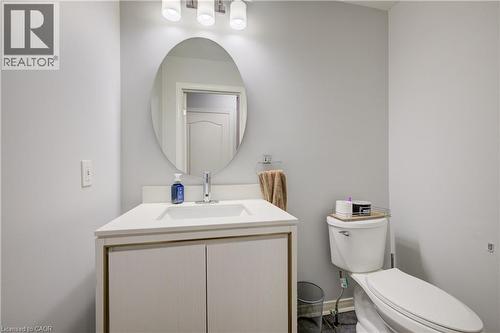 Bathroom featuring a white vanity with integrated sink, chrome faucet, oval mirror, and a three-light fixture - 23 Buerkle Court, Kitchener, ON - Indoor Photo Showing Bathroom