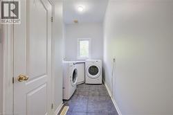 Dedicated laundry area featuring a front-loading washing machine and dryer, tiled flooring, and a single window - 