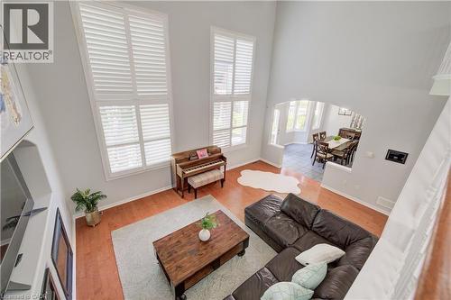 Living room featuring high ceilings, tall windows with white plantation shutters, wood-finish flooring, and an arched entry to the dining area - 23 Buerkle Court, Kitchener, ON - Indoor Photo Showing Other Room