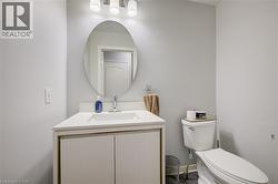 Bathroom featuring a white vanity with integrated sink, chrome faucet, oval mirror, and a three-light fixture - 