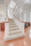 Carpeted staircase with white balusters and wood handrails - 
