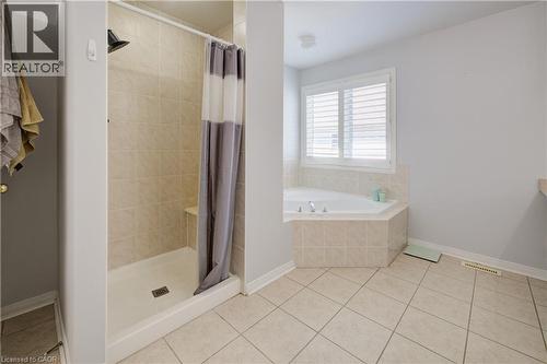 Bathroom featuring a tiled stand-up shower with a built-in bench, a corner soaking tub with tiled surround, and a window with white plantation shutters - 23 Buerkle Court, Kitchener, ON - Indoor Photo Showing Bathroom
