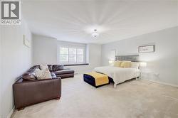 Spacious interior room featuring light-colored carpet flooring, white walls, and a window with white plantation shutters - 
