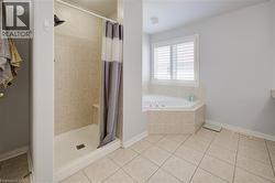 Bathroom featuring a tiled stand-up shower with a built-in bench, a corner soaking tub with tiled surround, and a window with white plantation shutters - 