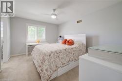 Bedroom featuring light gray wall paint, neutral carpet flooring, and a white ceiling fan with integrated lighting - 