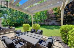 Spacious paver patio featuring a wooden pergola and manicured landscaping - 