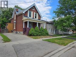 Brick exterior featuring a gabled roofline, white window shutters, and a covered front porch with pillars - 