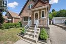 Brick exterior featuring a covered front porch with white railing, concrete steps, a paved driveway, and a detached two-car garage - 75 Arnold Street, Kitchener, ON  - Outdoor With Facade 