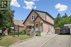 Brick exterior featuring a covered front porch with white railings and an awning - 