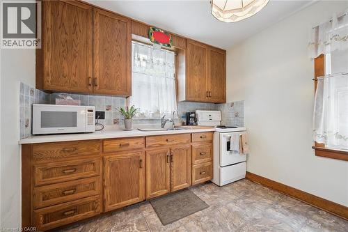 Kitchen featuring wood-finish cabinetry, light-toned countertops, and a tiled backsplash - 75 Arnold Street, Kitchener, ON - Indoor Photo Showing Kitchen