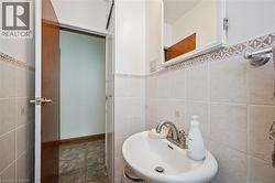 Pedestal sink with chrome faucet, light-toned wall tiling, decorative accent tile border, and mirrored medicine cabinet - 