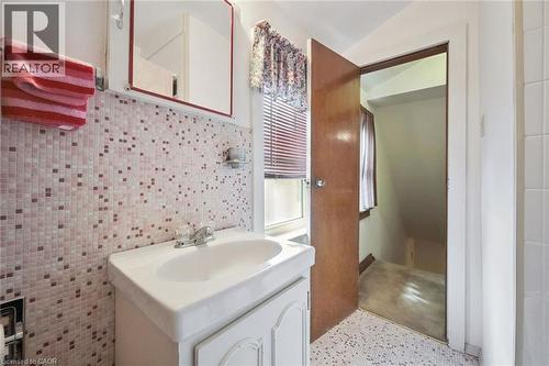 Bathroom featuring a vanity with a white basin and chrome faucet, mosaic tile backsplash, and a wall-mounted mirrored cabinet - 75 Arnold Street, Kitchener, ON - Indoor Photo Showing Bathroom