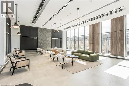 Spacious common area featuring an expansive window wall, contemporary track lighting, pendant lighting, textured wall paneling, and large format tile flooring - 50 S Grand Avenue S Unit# 1002, Cambridge, ON - Indoor Photo Showing Other Room