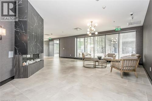 Modern lounge area featuring a linear fireplace with a dark marble-look surround and wood-finish base - 50 S Grand Avenue S Unit# 1002, Cambridge, ON - Indoor Photo Showing Other Room