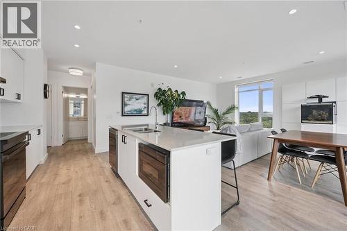 Open-concept living area featuring light wood-finish flooring, recessed ceiling lighting, and a kitchen island with an integrated sink - 50 S Grand Avenue S Unit# 1002, Cambridge, ON - Indoor