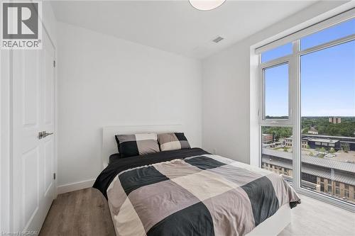 Bright room featuring a large window with city architecture and distant tree canopy - 50 S Grand Avenue S Unit# 1002, Cambridge, ON - Indoor Photo Showing Bedroom