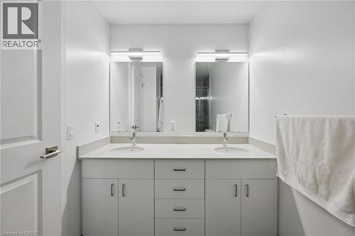 Modern double vanity featuring two integrated sinks, light-toned countertop, and dual mirrors with overhead strip lighting - 50 S Grand Avenue S Unit# 1002, Cambridge, ON - Indoor Photo Showing Bathroom