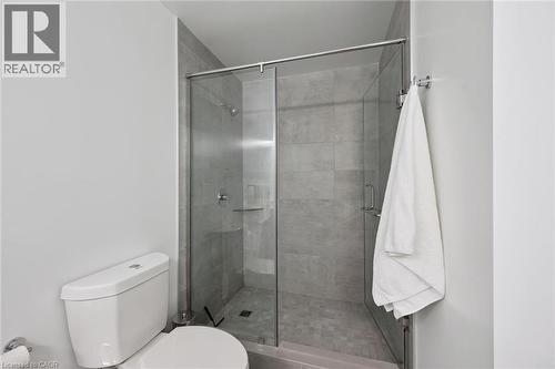 Glass-enclosed shower with full-height gray tile surround, mosaic tile shower pan, and chrome fixtures - 50 S Grand Avenue S Unit# 1002, Cambridge, ON - Indoor Photo Showing Bathroom