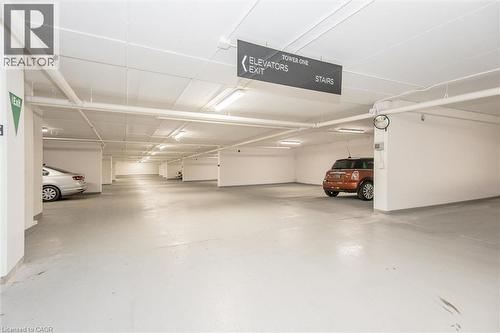 Subterranean parking garage featuring painted concrete floors, white structural pillars, and overhead fluorescent lighting - 50 S Grand Avenue S Unit# 1002, Cambridge, ON - Indoor Photo Showing Garage
