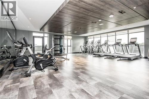 Fitness center featuring a patterned wood-finish flooring, full-height windows, a mirrored wall, and a wood-paneled ceiling - 50 S Grand Avenue S Unit# 1002, Cambridge, ON - Indoor Photo Showing Gym Room