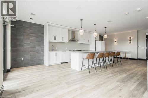 Contemporary kitchen featuring a large island with pendant lighting, stainless steel hood range, white cabinetry, and a textured accent wall - 50 S Grand Avenue S Unit# 1002, Cambridge, ON - Indoor Photo Showing Kitchen With Upgraded Kitchen