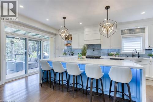 Kitchen featuring a light blue island with under-cabinet lighting, white countertops, and wood-finish flooring - 71 Ian Ormston Drive, Waterloo, ON 