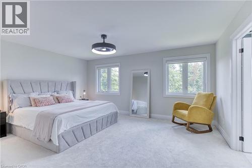 Expansive bedroom featuring light gray carpeting, two large windows with white trim, and a contemporary ceiling light fixture - 71 Ian Ormston Drive, Waterloo, ON 
