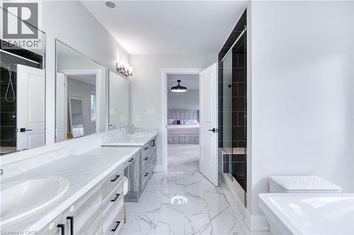 Bathroom featuring a dual vanity with light-toned wood-finish cabinetry and white countertops, a walk-in shower with dark subway tile surround, a built-in shower bench, and white marble-look floor til - 71 Ian Ormston Drive, Waterloo, ON 