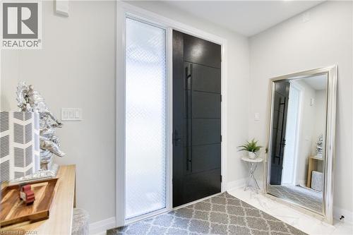 Modern entry featuring a paneled door with long pulls, a textured sidelight, and light-toned flooring - 71 Ian Ormston Drive, Waterloo, ON 