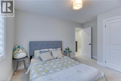 Carpeted room featuring light gray walls, a window with vertical blinds, and a white interior door with black hardware - 71 Ian Ormston Drive, Waterloo, ON 