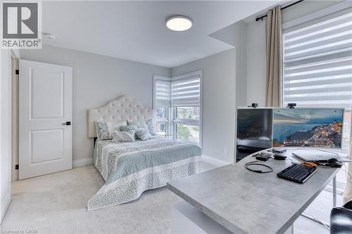 Bedroom featuring wall-to-wall carpeting, white interior door with black hardware, and an upholstered headboard - 71 Ian Ormston Drive, Waterloo, ON 