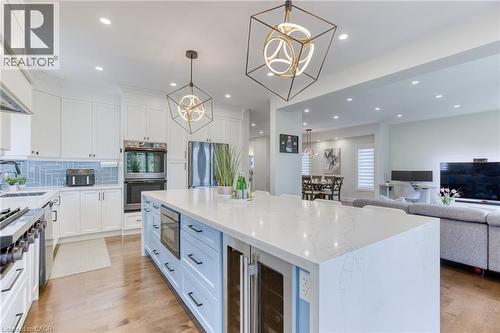 Modern kitchen featuring a large island with a light-colored countertop, integrated microwave, and beverage cooler - 71 Ian Ormston Drive, Kitchener, ON - Indoor Photo Showing Kitchen With Upgraded Kitchen