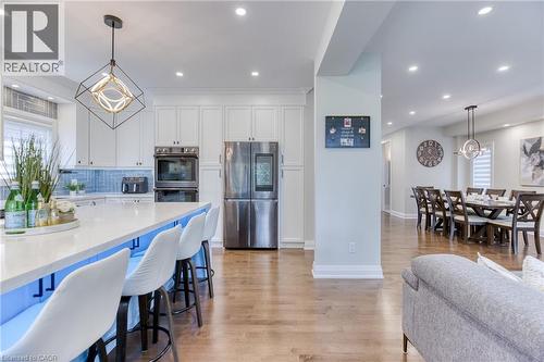 Spacious kitchen featuring white cabinetry, stainless steel appliances, a large island with seating, and wood-finish flooring - 71 Ian Ormston Drive, Kitchener, ON - Indoor