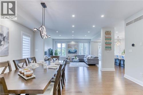 Open-concept living area featuring wood-finish flooring, recessed lighting, and a modern chandelier - 71 Ian Ormston Drive, Waterloo, ON 