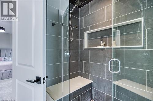 Modern shower enclosure featuring full-height grey tile, a built-in shower bench, a recessed niche, a handheld shower fixture, and a glass door - 71 Ian Ormston Drive, Kitchener, ON - Indoor Photo Showing Bathroom